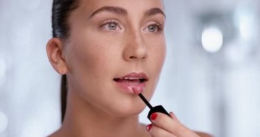 Beyaz arka plan önünde dudak parlatıcısı kullanan güzel kadın