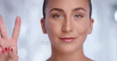 Güzel bir kadın beyaz bir arka plan önünde barış işareti yapar