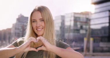 Bir kalp elleri ile modern bir bağlantı noktası infront yapma çekici sarışın kadın