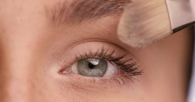 Çekici kadın kahverengi saçlı kozmetik fõrçayla yüzünde toz uygulamak