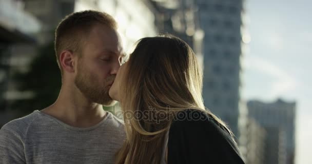 Retrato cercano de pareja joven en la ciudad besándose en hermosa retroiluminada — Vídeo de stock