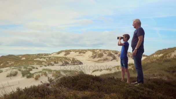 Grandchild on dune looking through binoculars — Stock Video