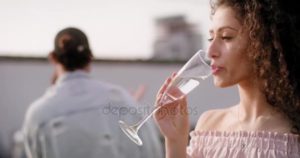 Jovem mulher de cabelos escuros bebendo com amigos no fundo — Vídeo de Stock