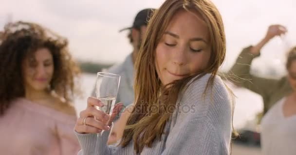 Junge braunhaarige Frau tanzt mit Glas in der Hand und Freunden im Hintergrund — Stockvideo