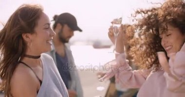İki genç kadın gözlük ellerinde ve arkadaşları arka planda dans