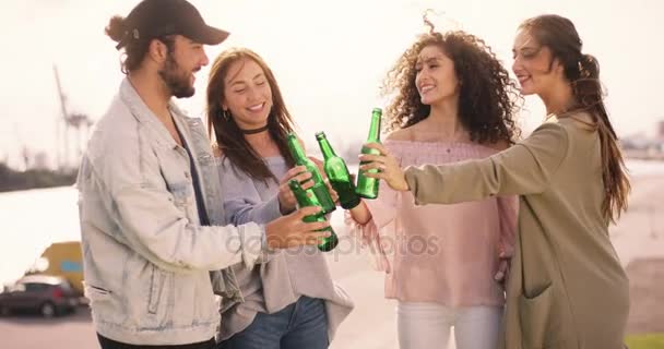 Jóvenes adultos multiétnicos tintinean botellas con un clima soleado — Vídeos de Stock