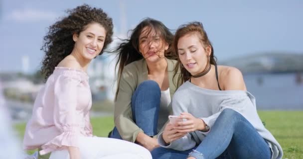 Belas namoradas sentadas fora com smartphone e flertando — Vídeo de Stock
