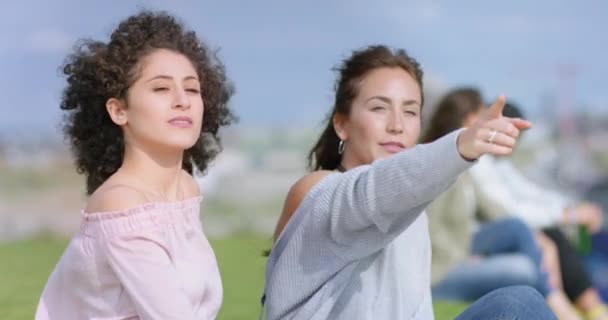 Привлекательные девушки снаружи и одна девушка указывает пальцем на что-то в небе — стоковое видео