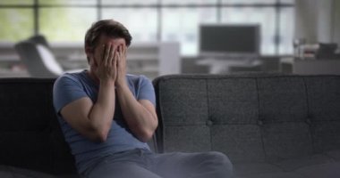 Umutsuzluk içinde elleri atma bir kanepede depresif genç adam