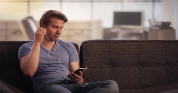 Νεαρός άνδρας, να ακούτε μουσική στον καναπέ του — Αρχείο Βίντεο