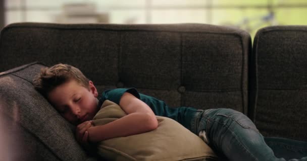 Pojke som sover på soffan håller en kudde — Stockvideo
