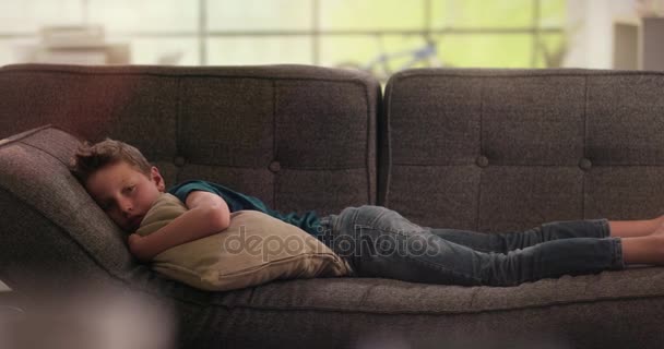 Anak laki-laki berbaring sedih di sofa sambil memegang bantal — Stok Video