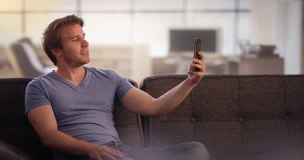 Νεαρός άνδρας στον καναπέ κάνει selfies — Αρχείο Βίντεο