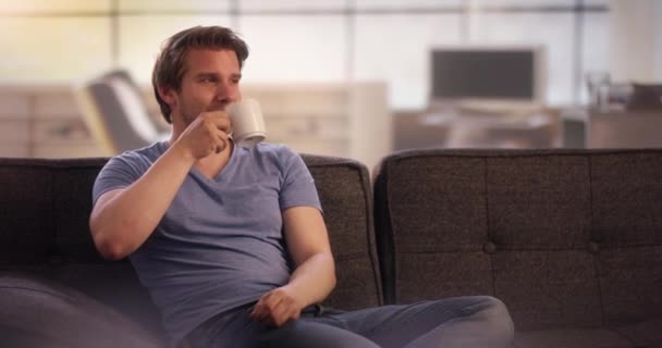 Jongeman koffie drinken op zijn bank — Stockvideo