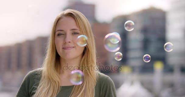 Attraente giovane donna circondata da bolle di sapone sorride nella fotocamera — Video Stock