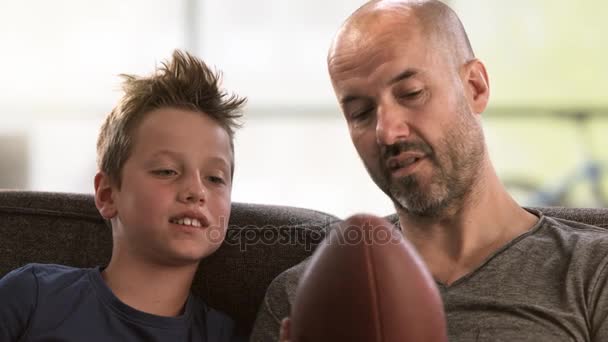 Vater erzählt seinem Sohn auf der Couch vom Fußball — Stockvideo