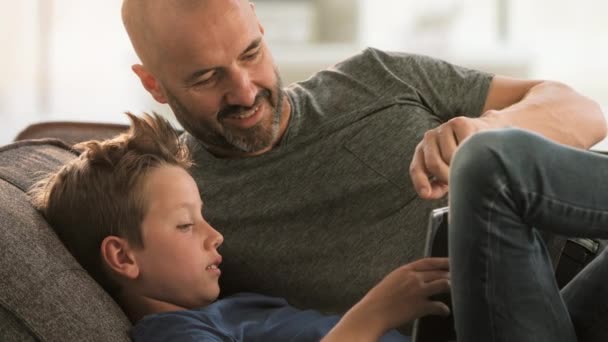 Padre e hijo mirando Tablet en el sofá — Vídeos de Stock