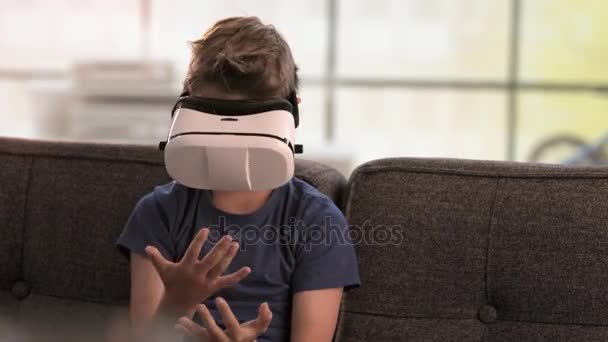 Boy utiliza auriculares de realidad virtual en el sofá — Vídeos de Stock