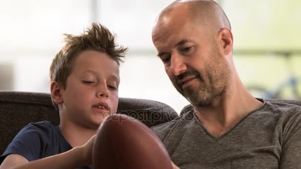 Vater erzählt seinem Sohn auf der Couch vom Fußball — Stockvideo