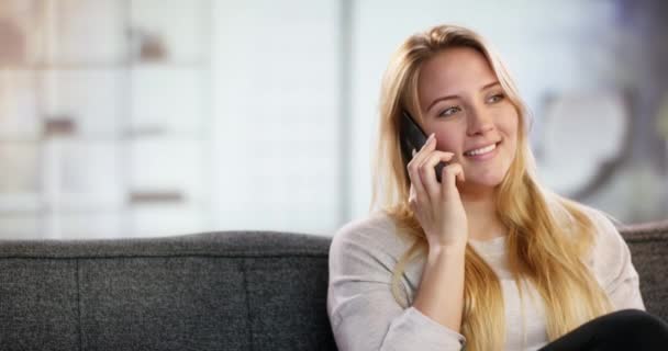 Šťastná žena mluvit na mobilním telefonu sedí na gauči doma — Stock video