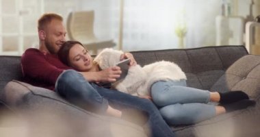 Sarılma ve tablet komik şeyler izlerken kanepede serin Çift