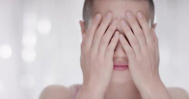 Yüzünü elleriyle açığa ve kameraya gülme genç kadın