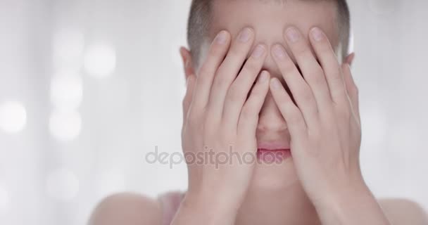 Junge Frau zeigt ihr Gesicht mit den Händen und lacht in die Kamera — Stockvideo