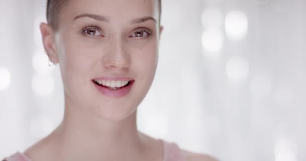 Mladá dívka s krátkými vlasy obrací svou hlavu na kameru a usmívá se — Stock video