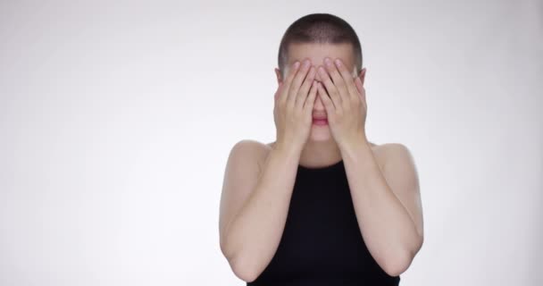 Ung kvinna avslöjar henne med händerna dolda ansikte och leenden — Stockvideo