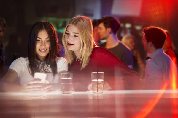 Dos Chicas Atractivas Jóvenes Mirando Teléfono Inteligente Bar Reír —  Fotos de Stock