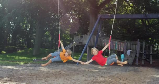 Zwei Kinder Schwingen Händchen Haltend Zusammen — Stockvideo