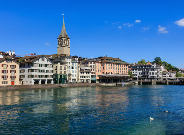 Zurich, Switzerland - 18 June, 2017: old town buildings along the Limmat river, clock tower of the St. Peter Church, Hotel Storchen. Zurich is the largest city in Switzerland and the capital of the Swiss canton of Zurich.