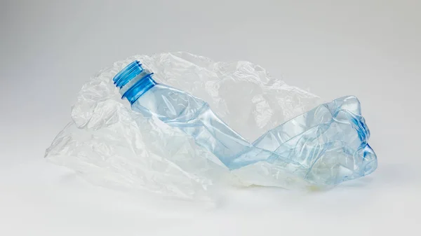 Plastic bottle with cellophane bag on a light background. The concept of ecology. — Stock Photo, Image