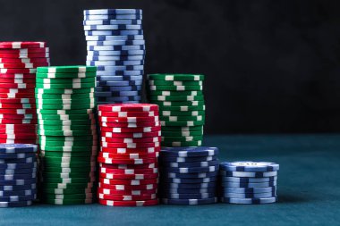Siyah arka planda mavi bir masada poker çipleri yığını