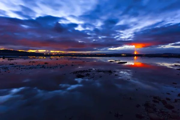 Llama en el horizonte de la escena del paisaje nublado nocturno sobre la superficie del agua — Foto de Stock