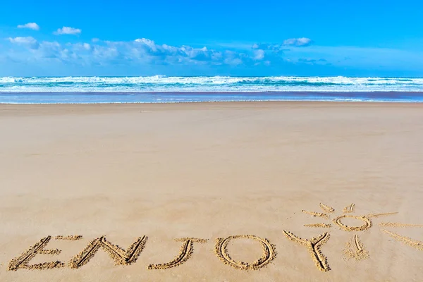Desfrute de inscrição na areia da praia molhada sob o sol desenho e se — Fotografia de Stock