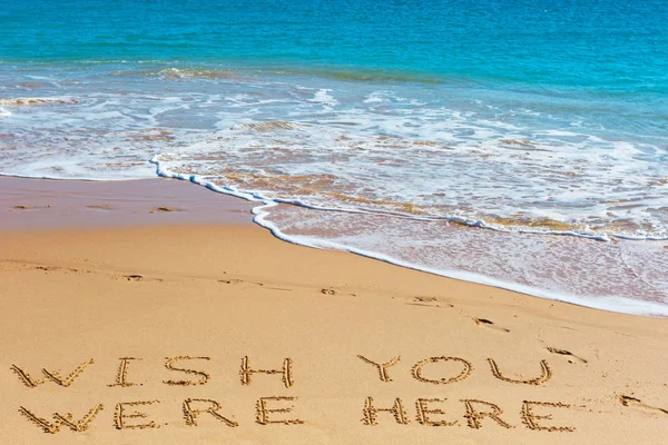 DESIDERI QUI iscrizione sulla sabbia bagnata della spiaggia con il mare turchese — Foto Stock