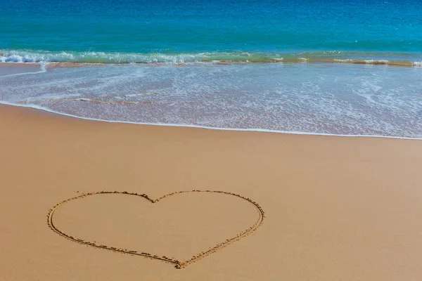 Изображение сердца на мокром пляже с бирюзовым морем на заднем плане — стоковое фото