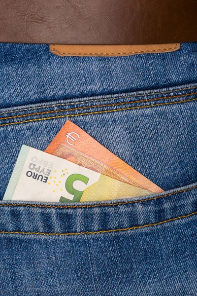 Primer plano de cinco billetes de euro asomándose por los pantalones vaqueros azules poc —  Fotos de Stock