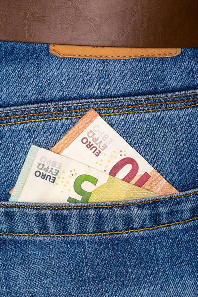 Primer plano de los billetes de cinco y diez euros que asoman por los pantalones vaqueros azules —  Fotos de Stock