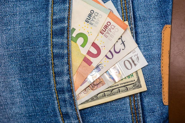 Closeup of various countries banknotes peeking out of blue jeans — Stock Photo, Image
