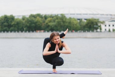 Yoga asanas şehrin waterfro üzerinde pratik bir genç kadın