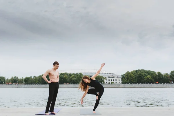 Un hombre joven y una mujer practicando yoga asanas en la ciudad en th — Foto de Stock