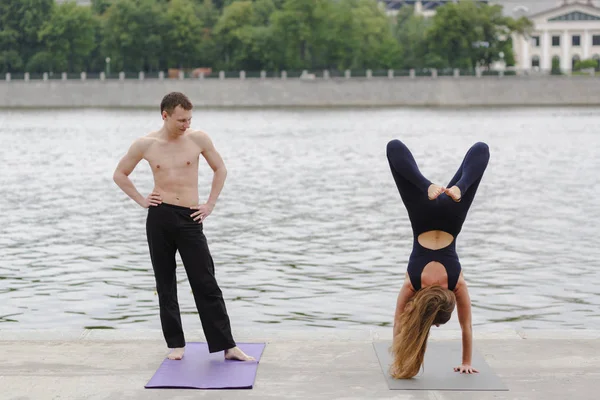 En ung man och en kvinna som tränar yoga asanas i staden på th — Stockfoto