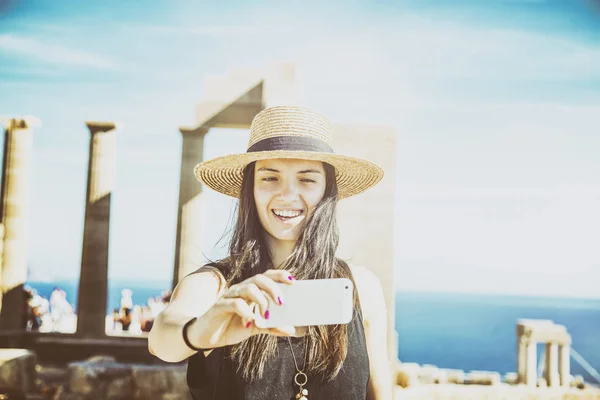 Beautiful young woman in a hat makes selfie on the background of — Stock Photo, Image