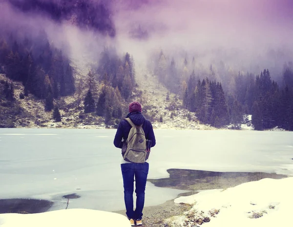 Chica turista con una mochila de pie en la orilla de un congelado l — Foto de Stock