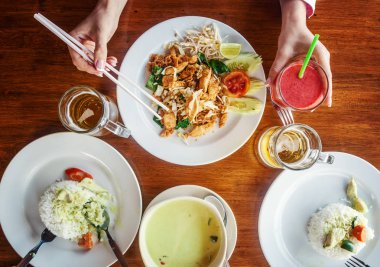 Bir grup insan masada yemek yiyor olması. Belgili tanımlık resim yukarıda. T