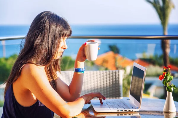 Jonge mooie vrouw met lang donker haar zitten met een laptop — Stockfoto