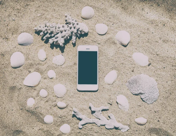 Smartphone in the sand with shells and corals, business and tech — Stock Photo, Image