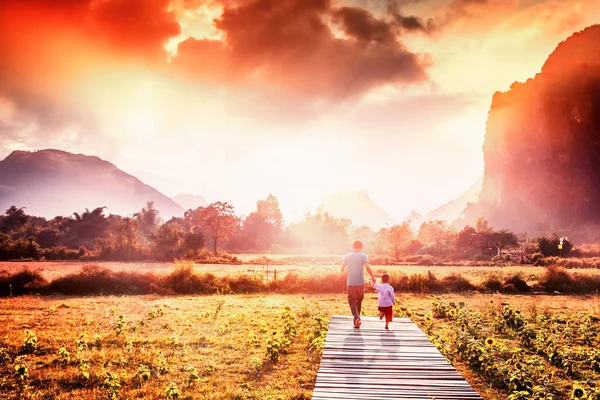 Man with a young son go down the path at sunset on a background — Stock Photo, Image